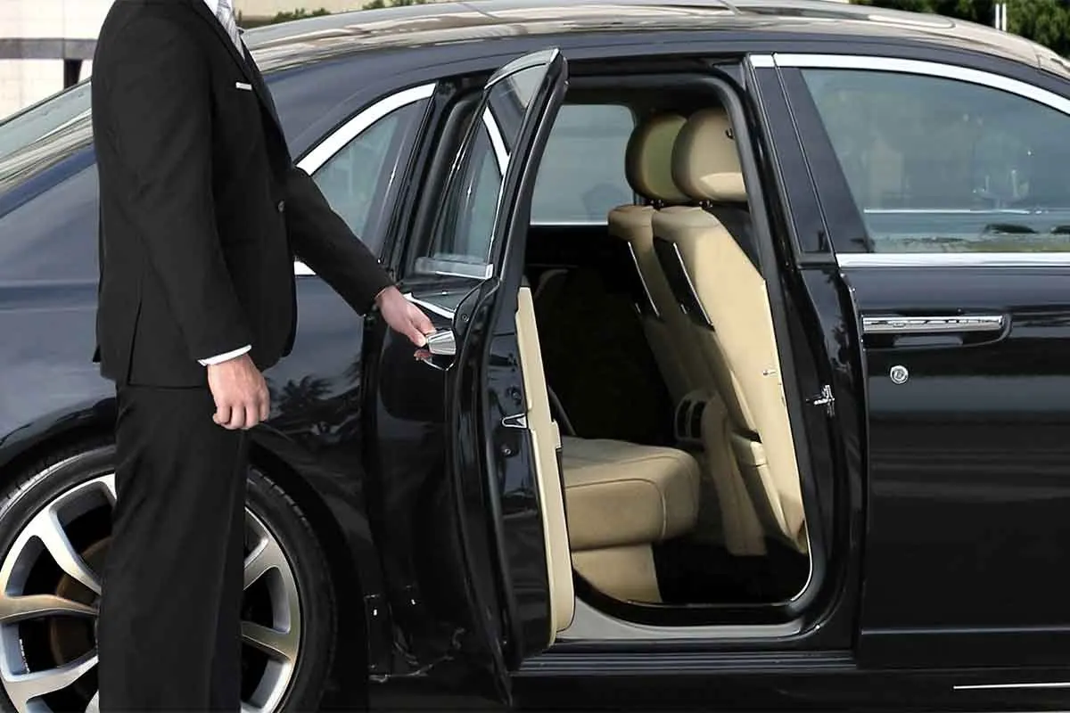 Leather rear cabin of a luxury sedan with chauffeur holding the door