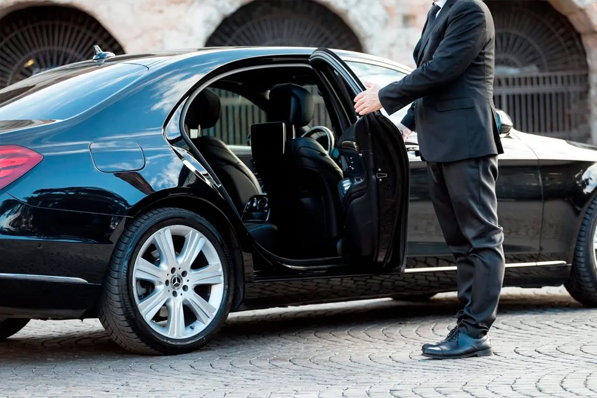 Chauffeur opening the rear door of a black sedan